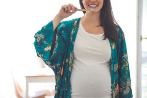 pregnant woman brushing her teeth