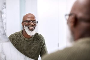 man with beard looking in mirror, smiling