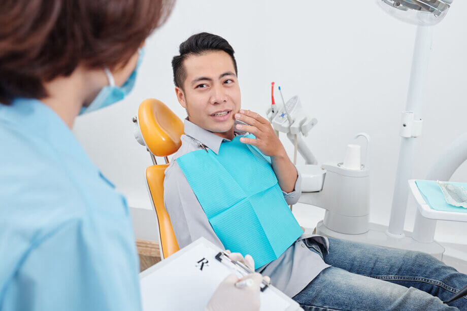 Man holding mouth talking to dentist