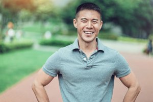 smiling man in grey polo standing outside