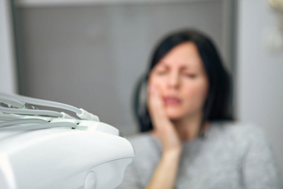 blurry image of woman holding jaw in pain