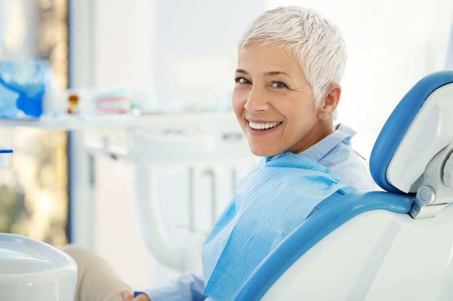 smiling older woman with short grey hair sitting in dental exam chair