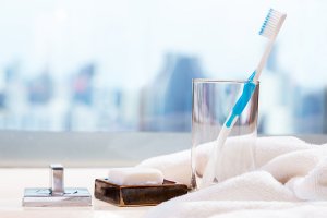 toothbrush in glass next to bar of soap and towel