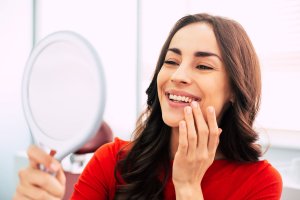 smiling woman looking in hand mirror