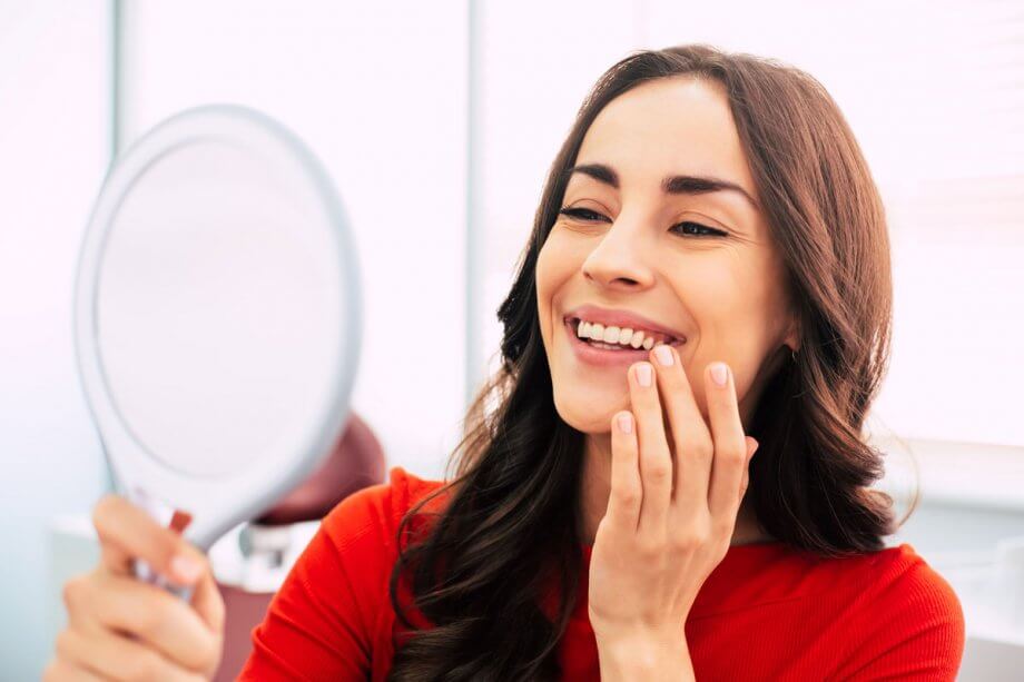 smiling woman looking in hand mirror