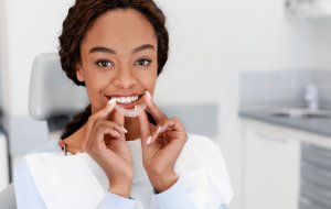 woman in dental chair, holding aligner